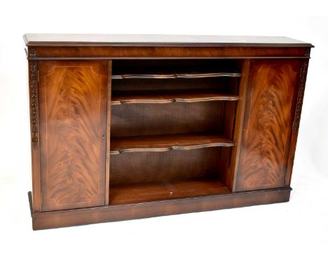 A 20th century bookcase cabinet with two central shelves, cupboard door to either side, with ornate leaf and floral decoratio