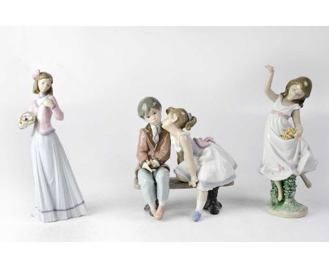 LLADRÓ; three figures comprising a young girl and boy sitting on a bench, height 19cm, a young girl holding flowers in her sk