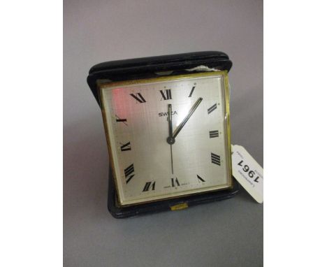 Blue leather cased travelling alarm clock, the silvered dial with Roman numerals, having Swiss movement