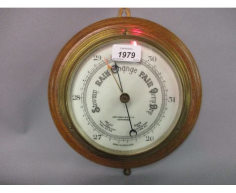 Circular brass ships bulk head barometer with oak mount, the dial inscribed John Barker and Co. Kensington