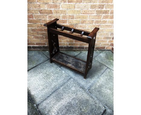 AN ARTS & CRAFTS STYLE OAK STICK STAND  with pierced decoration to the ends and inset metal drip tray, 67cm wide 27cm deep 74