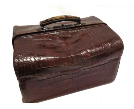 A VICTORIAN TRAVELLING TOILET SET in a crocodile skin bag with outer cloth cover, containing five silver topped hobnail cut g