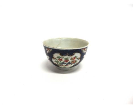 AN EARLY WORCESTER TEA BOWL  painted with flowers within gilt cartouches on a scale blue ground, 7.5cm diameter, blue square 