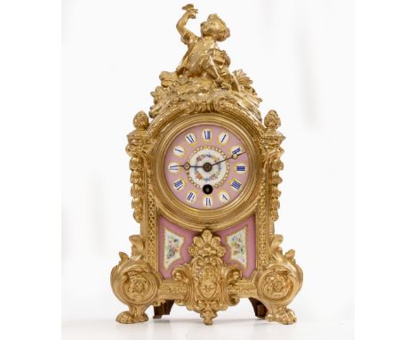 A GILT SPELTER PORCELAIN MOUNTED TIMEPIECE  or clock, the case surmounted by a sculpture of a boy freeing a bird from a cage,