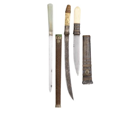 the first with slender single-edged blade, plain white ferule and pale green stone grip, in its carved wooden scabbard decora