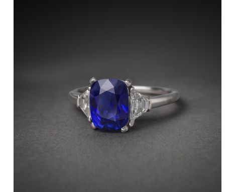 A sapphire and diamond three stone ring, the cushion-shaped sapphire weighing 3.51 carats set within trapeze-cut diamond shou