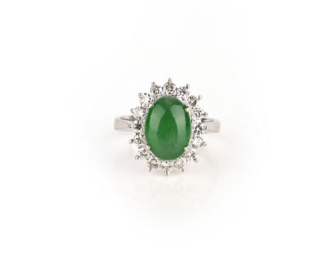 A jade and diamond cluster ring, the oval jade cabochon set within a surround of round brilliant-cut diamonds in white gold, 