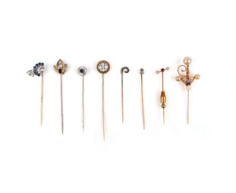 A group of eight stick pins, with finial designs including: a diamond cluster in a rope twist border; a ruby between seed pea