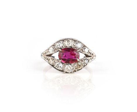 A ruby and diamond set stylised eye ring, the oval shaped ruby is set within ten circular cut diamonds in white gold, size N 