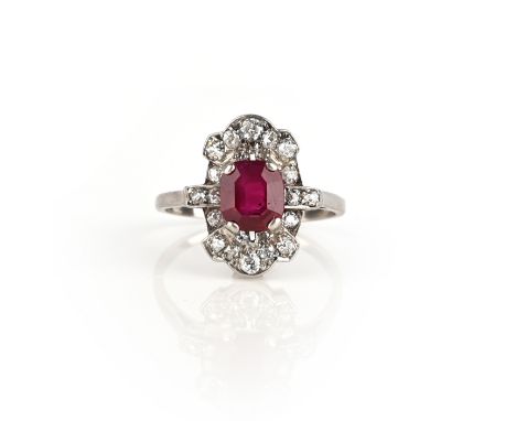 A ruby and diamond ring, early 20th century, claw-set with a step-cut ruby, within a border of cushion-shaped and circular-cu