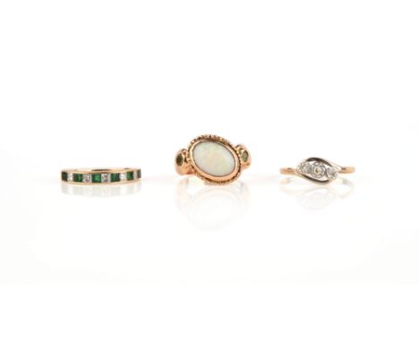 A group of three rings, including a ring set with a cabochon opal between shoulders set with circular-cut peridots, size N, B