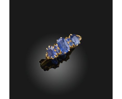 A sapphire ring, the three principal cushion-shaped sapphires spaced by smaller pairs of circular-cut sapphires, yellow gold,