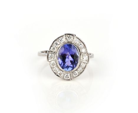 A tanzanite and diamond ring, of cluster design, set with an oval tanzanite weighing 2.10 carats, within a millegrain border 