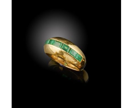 A gold and emerald ring, Pierre Brun, mid 20th century, of bombé design, centring on a line of channel-set calibré-cut emeral