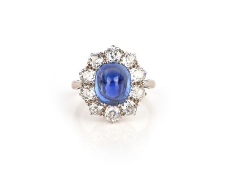 A sapphire and diamond ring, circa 1900, of cluster design, claw-set with a sugarloaf sapphire within a border of cushion-sha