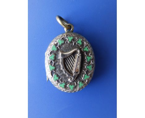 A late 19thC Irish gold coloured oval locket, decorated with a raised harp surrounded by a garland of green enamelled clover 
