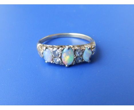 A three stone opal ring with small diamonds.