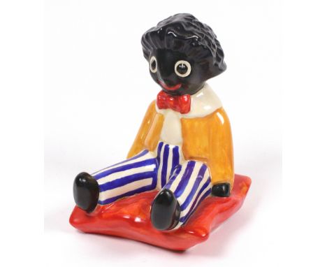A Clarice Cliff, Wilkinson, seated Golliwogg bookend, on an orange cushion, printed marks and honey glaze, 16cm high.