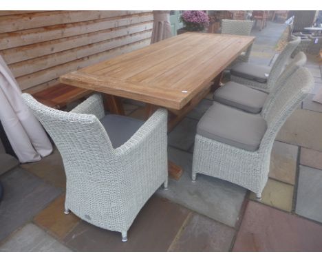 A Bramblecrest Kuta teak table with a bench, two armchairs and three sidechairs, cushions and parasol