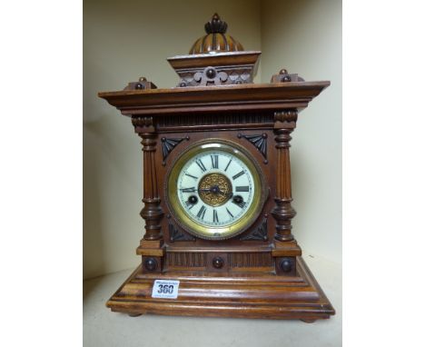 An eight day striking mantel clock with a porcelain dial in a walnut case with key and pendulum - Height 40 cm 