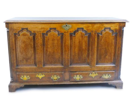 An 18th century oak mule chest, the hinged oblong top with moulded edge, over a fascia of four arched fielded panels and two 