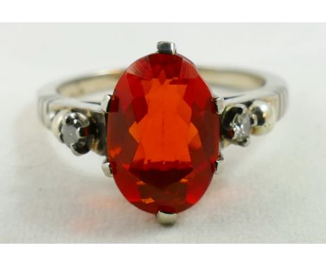 A 14ct white gold fire opal and diamond three stone ring, claw set with a mixed cut stone, flanked by brilliants, size M.