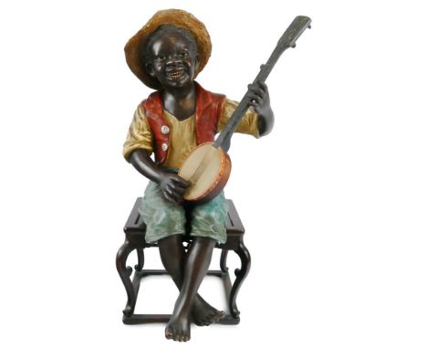 A late 19th century Bretby polychrome terracotta figure of a seated black banjo player, the young boy wearing a straw hat, wh