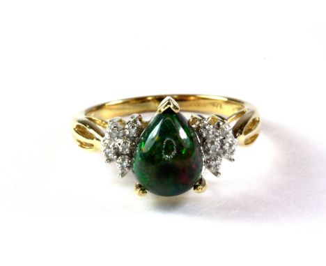 An unusual 9ct gold ring set with a teardrop shaped green opal with diamond set shoulders. (M).