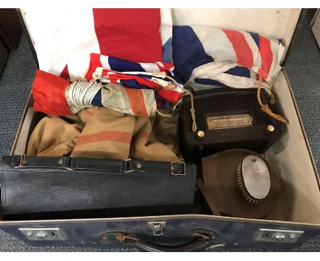 A large vintage suitcase containing a naval duffel coat, canvas bag, flags, vintage radio, etc.