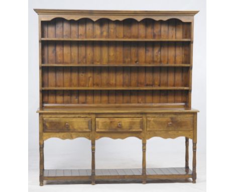 A Reproduction stained beech wood and pine dresser 
With a moulded cornice above a shaped frieze, 3 enclosed shelves, the bas