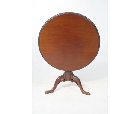 A George III mahogany tripod table 
With a 85cm diameter top with a leaf and flower carved border raised upon a turned barrel