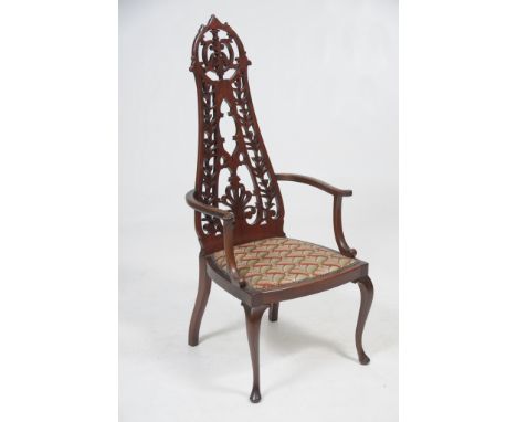 An Edwardian mahogany elbow chair
With a waisted leaf and anthemion pierced back, padded tapestry seat raised upon cabriole f