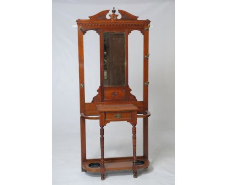 A Victorian walnut hall stand
With an architectural  leaf carved pediment above a bevelled mirror and five brass acorn finial