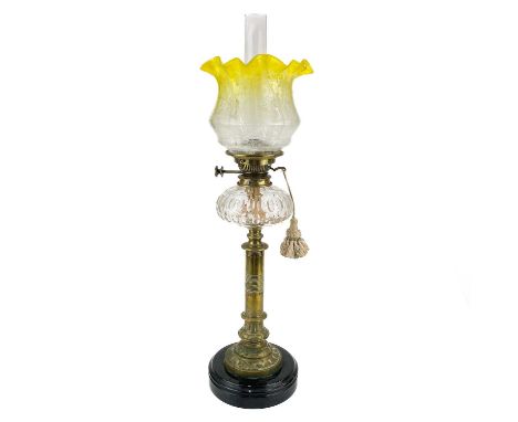 A Victorian brass oil lamp with a glass reservoir and etched yellow shade.  On a circular base, clear glass oil reservoir and