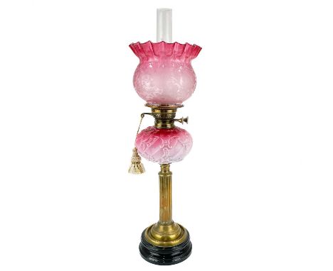 A Victorian brass oil lamp with a glass oil reservoir and cranberry shade.  With circular base, moulded cranberry reservoir a