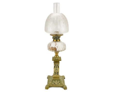 A Victorian brass oil lamp with a clear glass oil reservoir and an etched glass shade.  On a decorative brass base, with clea