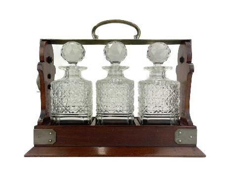 A Betejeman's patent three bottle mahogany tantalus. With silver plated fittings, and stamped marks, height 29cm, width 36cm.