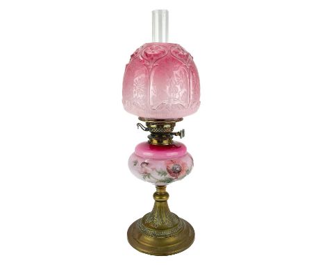 A Victorian brass oil lamp with a pink glass reservoir and cranberry shade.  With a pink glass oil reservoir painted with flo
