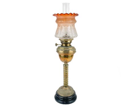 A Victorian brass oil lamp with a brass oil reservoir and an etched orange glass shade.  Raised on a circular base, with spir
