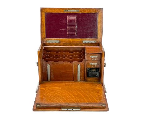 An Edwardian oak stationery cabinet. With rising lid and drop front with a fold-down writing surface, fitted with drawers, st