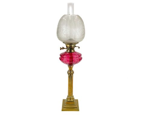 A Victorian brass oil lamp with glass shade.  With cranberry glass oil reservoir and an etched glass shade, height 73cm.Vario