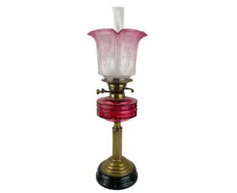 A Victorian brass oil lamp with a cranberry reservoir and cranberry glass shade.  Raised on circular base, with an etched cra