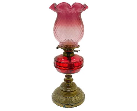 A Victorian brass oil lamp with a cranberry glass shade.  Raised on a circular base, with a cranberry oil reservoir and a cra