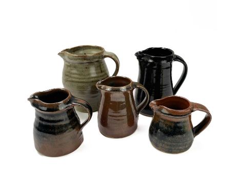 A Leach Pottery standard ware jug. Together with four other Leach Pottery jugs, various marks, largest 16cm.The large jug has