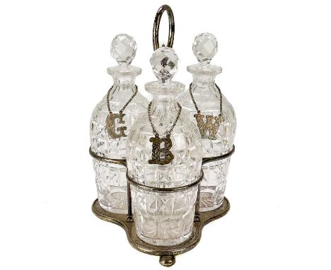 A late Victorian three bottle silver plated decanter stand. With ring handle and fitted with three panel cut decanters and st