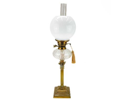 A Victorian brass oil lamp with a clear glass oil reservoir and white glass shade.  Raised on a square brass base, height 70c