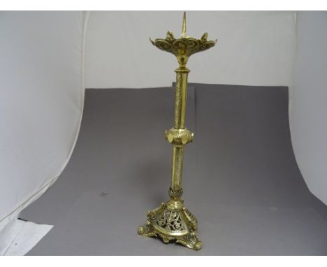 A large decorative brass candlestick with pierced decoration, along with a pair of brass candlesticks    