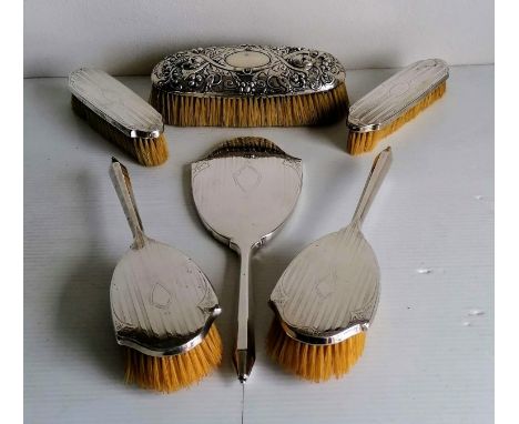 A Georgian silver-backed clothes brush with rococo decoration, marks rubbed, 20 cm, a George V five-piece brush set with engi