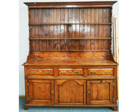 A GEORGE II SOLID YEW-WOOD DRESSERThe enclosed plate rack over three drawers and cupboards, on bracket feet, 181cm wide; 203c