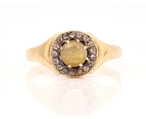 A GOLD, CHRYSOBERYL CAT'S EYE AND DIAMOND CLUSTER RINGMounted with the circular cat's eye within a surround of rose cut diamo